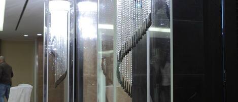 Een moderne lobby met een glazen lift en een kroonluchter.