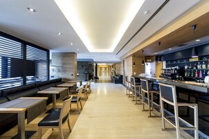 Un área de bar moderna con mobiliario de madera y una barra alargada.