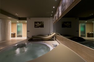 Un spa moderno con un amplio jacuzzi, suelo de madera y decoración minimalista.