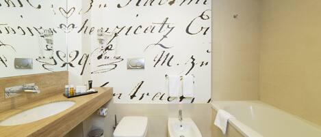 Une salle de bain moderne avec un grand miroir, un lavabo, un bidet et une baignoire.