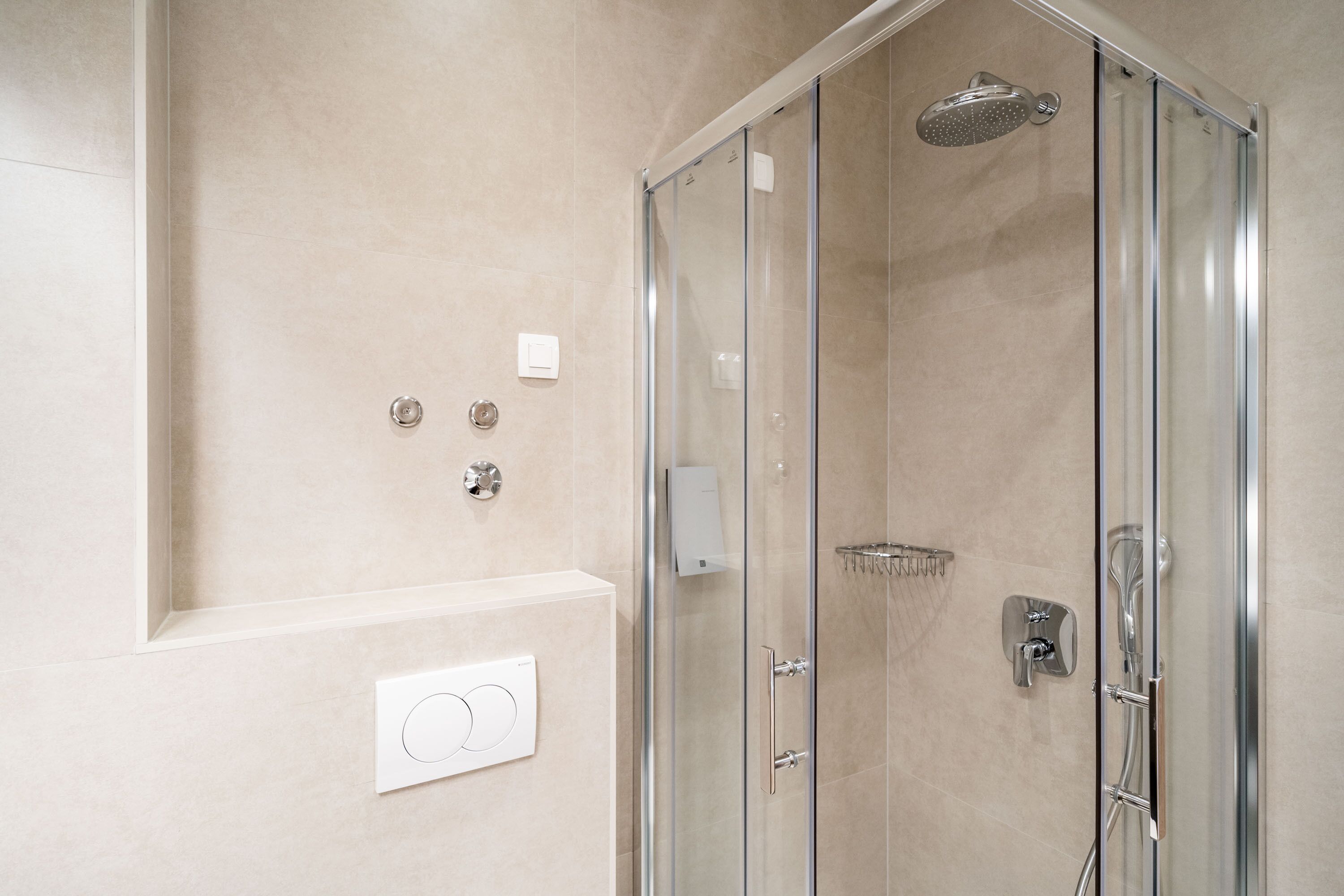 Une salle de bain moderne dotée d’une douche à parois de verre, d’un panneau de commande mural et d’un pommeau de douche chromé.