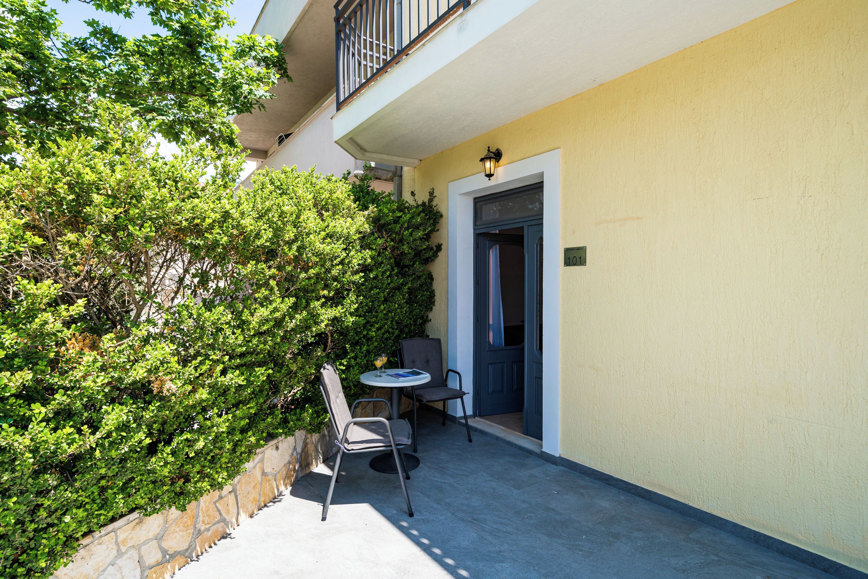 Un patio al aire libre con una mesa, sillas, una puerta y un muro de piedra.