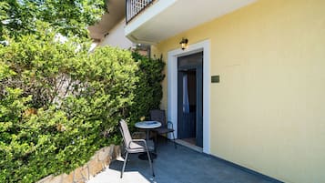 Un patio al aire libre con una mesa, sillas, una puerta y un muro de piedra.