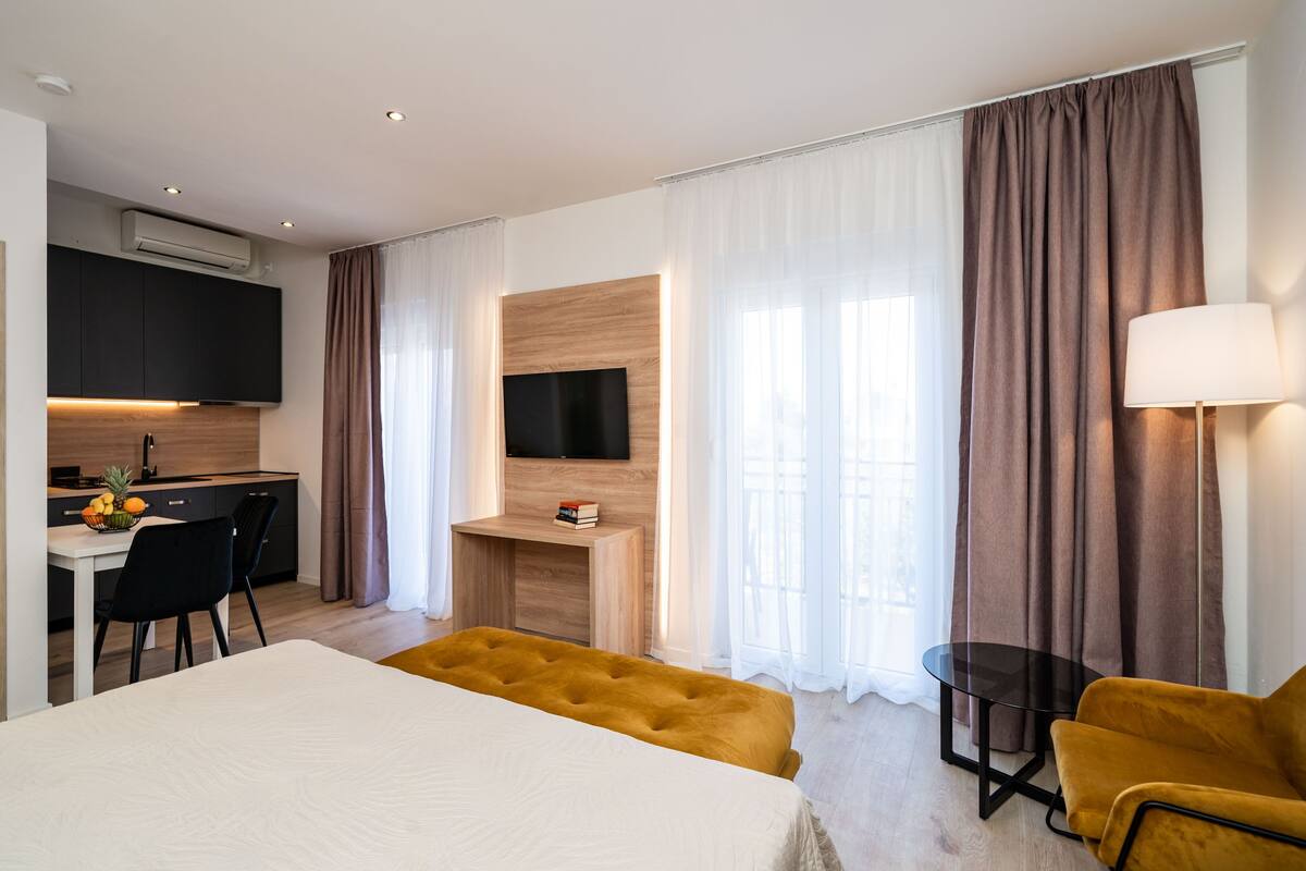 Una habitación de hotel moderna con una cama, un escritorio, un televisor y un sofá.