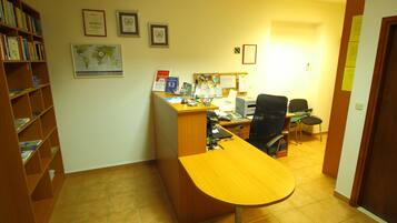Una oficina con un escritorio de madera, una computadora y una estantería. Hay diplomas enmarcados en la pared.