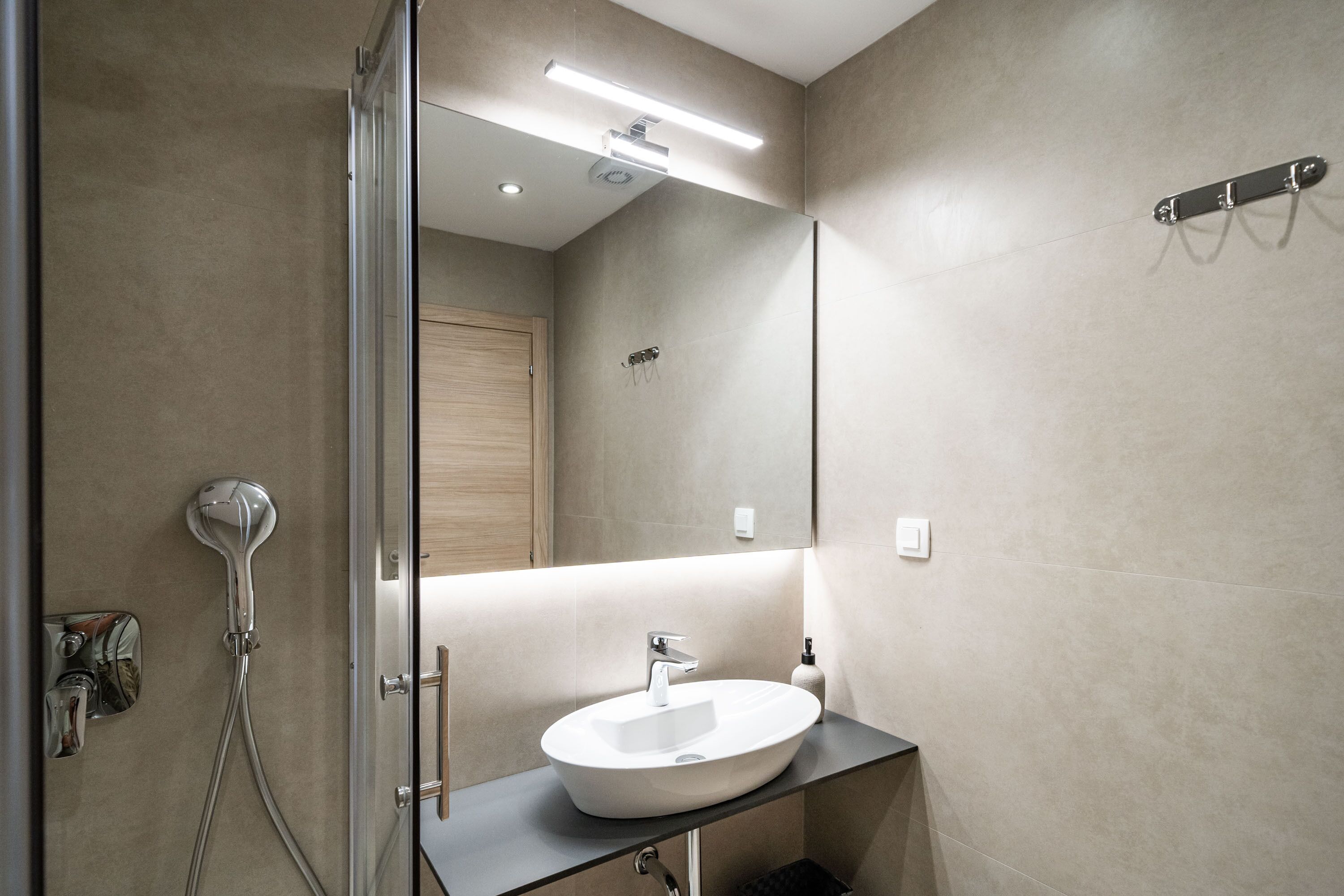 Een moderne badkamer met een grote spiegel, een wastafel en een douche.