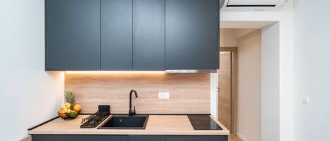 A modern kitchen with dark cabinets, a black sink, and a wooden countertop.