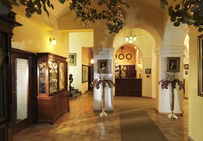 Eine Hotelhalle im klassischen Stil, mit einer imposanten Treppe, stilvollem Mobiliar und dekorativer Beleuchtung.