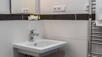 Een moderne badkamer met een wit wastafelmeubel, een spiegel, een handdoekhouder en een toilet.