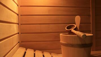 Een sauna met houten banken en een houten emmer met een houten lepel.