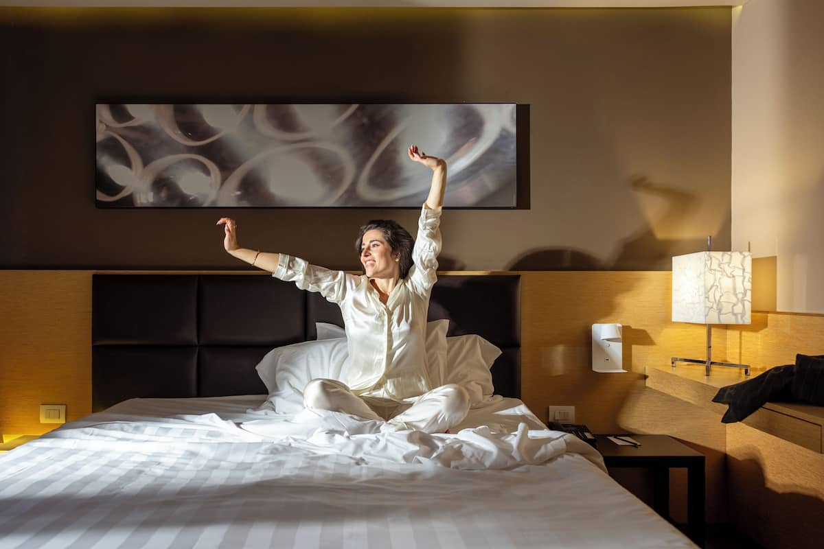 Habitació d'hotel amb un llit, una tauleta de nit, una làmpada i una obra d'art penjada a la paret.