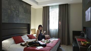 Una habitación de hotel con una cama grande, un escritorio y una televisión.