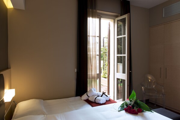 A hotel room with a bed, a chair, and a view of the outside.
