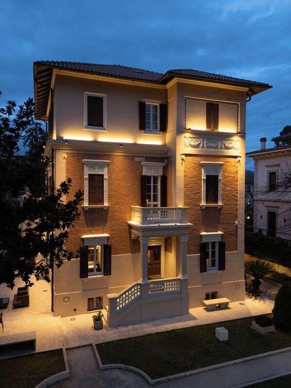 A multi-story building with a balcony, a staircase, and a well-maintained lawn.