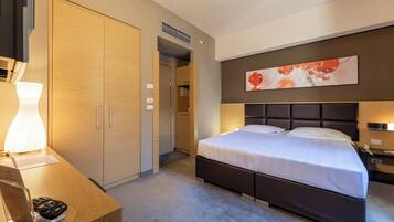 Una camera d'albergo con un letto, un comodino, una lampada e un quadro appeso al muro.