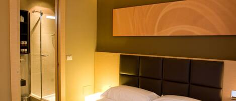 Quarto de hotel com cama, chuveiro e uma obra de arte pendurada na parede.