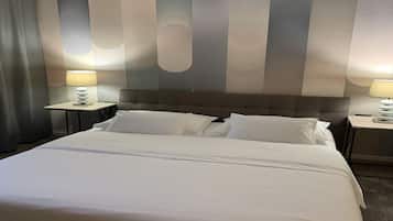 Habitación de hotel con una cama grande, dos mesitas de noche con lámparas y un diseño de pared a rayas.