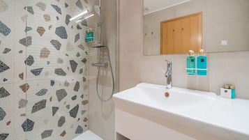 A modern bathroom with a white sink, a mirror, and a shower area.