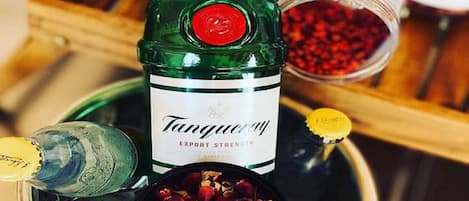 A bottle of Tanqueray Export Strength gin, a bottle of Absolut vodka, and a bowl of dried rose petals.