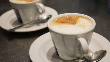 Dos tazas blancas de café con espuma, cada una con una cuchara sobre un platito.