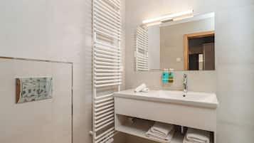 Un baño moderno con lavamanos, espejo y toallero blancos.
