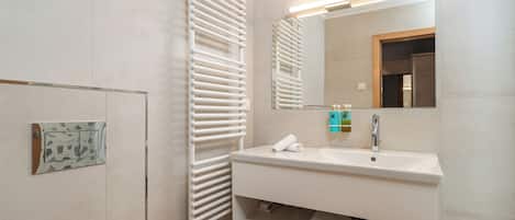 A modern bathroom with a white sink, mirror, and towel rack.
