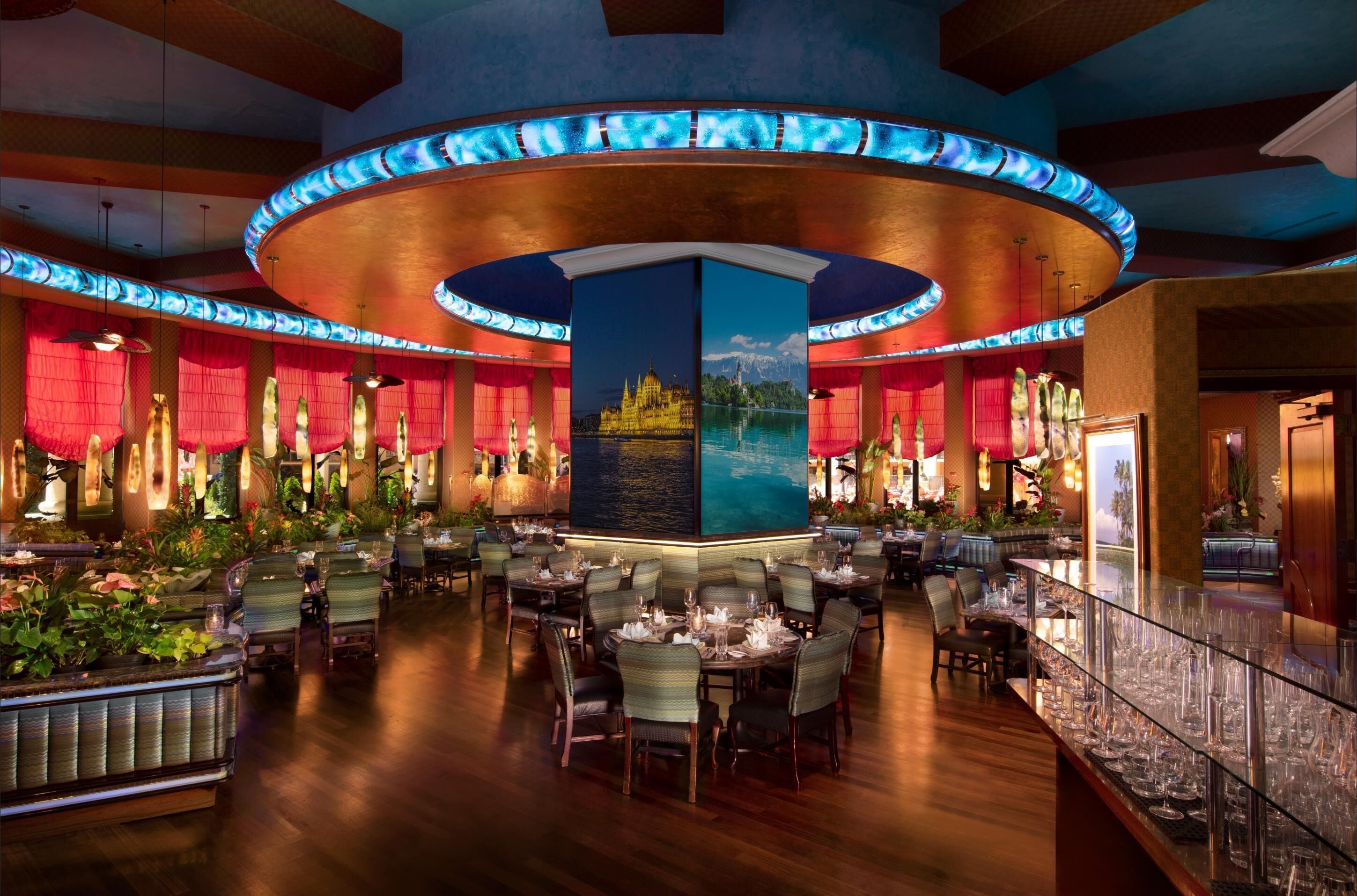 A restaurant with a central island, multiple tables, and red curtains.