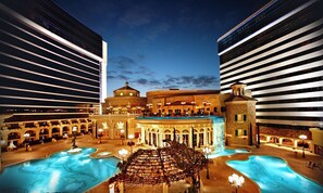 A hotel with multiple swimming pools, a central fountain, and a grand entrance with classical architecture.