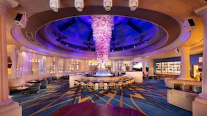 Un hall d’entrée spacieux avec un bar central, des espaces aménagés pour s’asseoir et un décor original au plafond.
