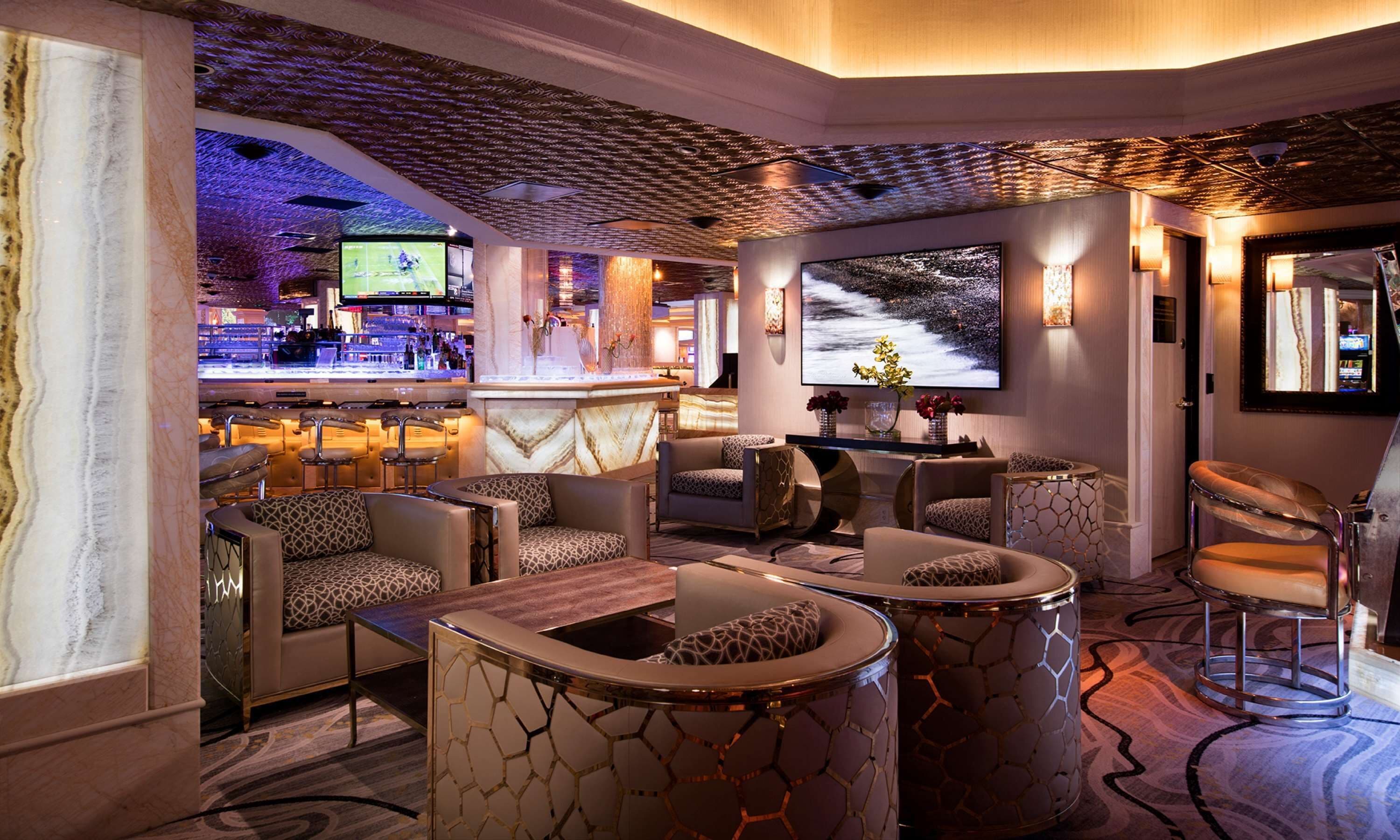 A modern lounge area with a bar, comfortable seating, and a large TV screen.