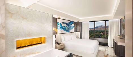 A modern hotel room with a large bed, a bathtub, a painting, and a view of the mountains.