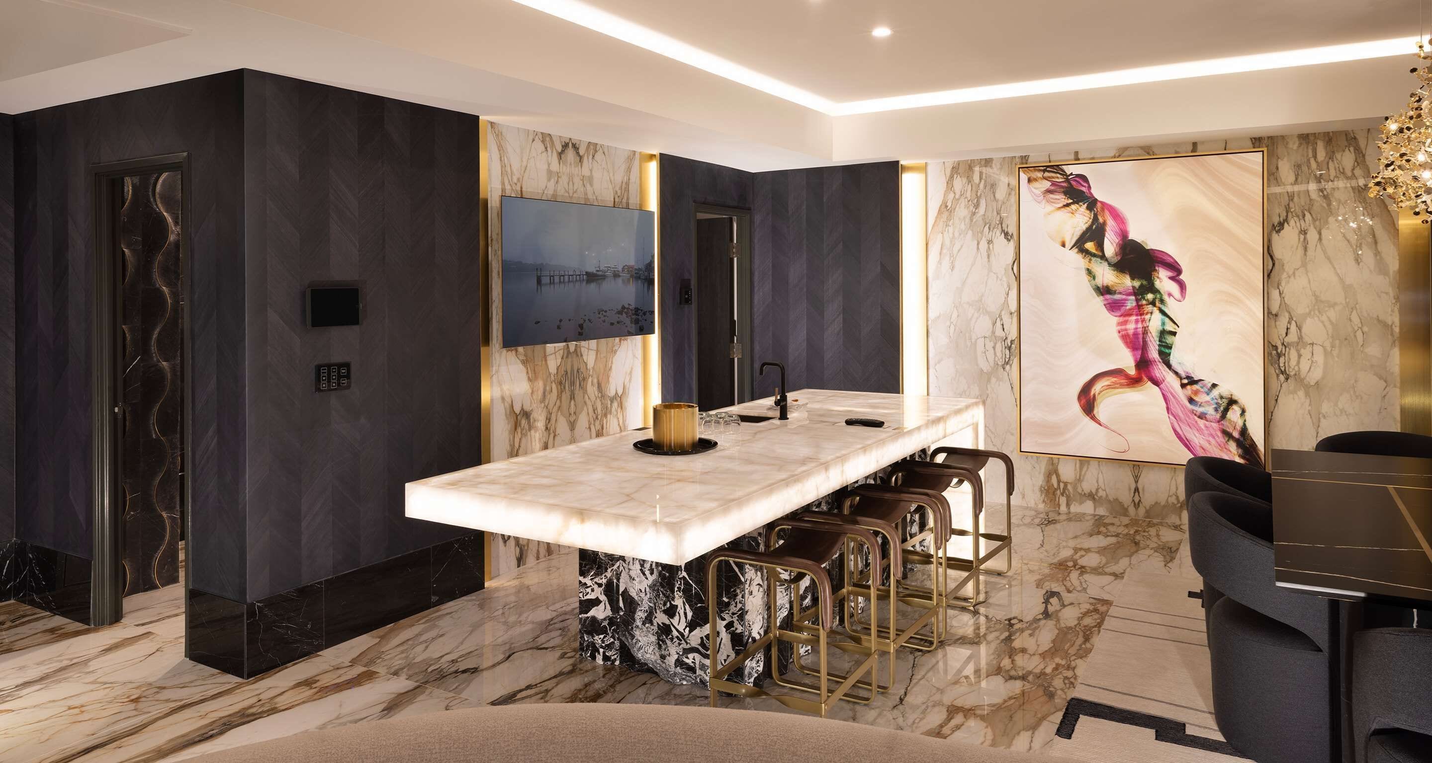 A modern bathroom with a marble vanity, a large mirror, and a bar area with stools.