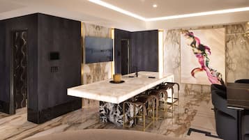 A modern bathroom with a marble vanity, a large mirror, and a bar area with stools.
