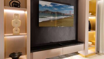 A modern interior with a TV mounted on a dark wall, a wooden shelf with decorative items, and a marble countertop.