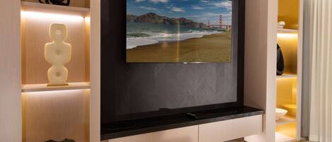 Un interior moderno con un televisor montado en una pared oscura, una repisa de madera con adornos y una encimera de mármol.