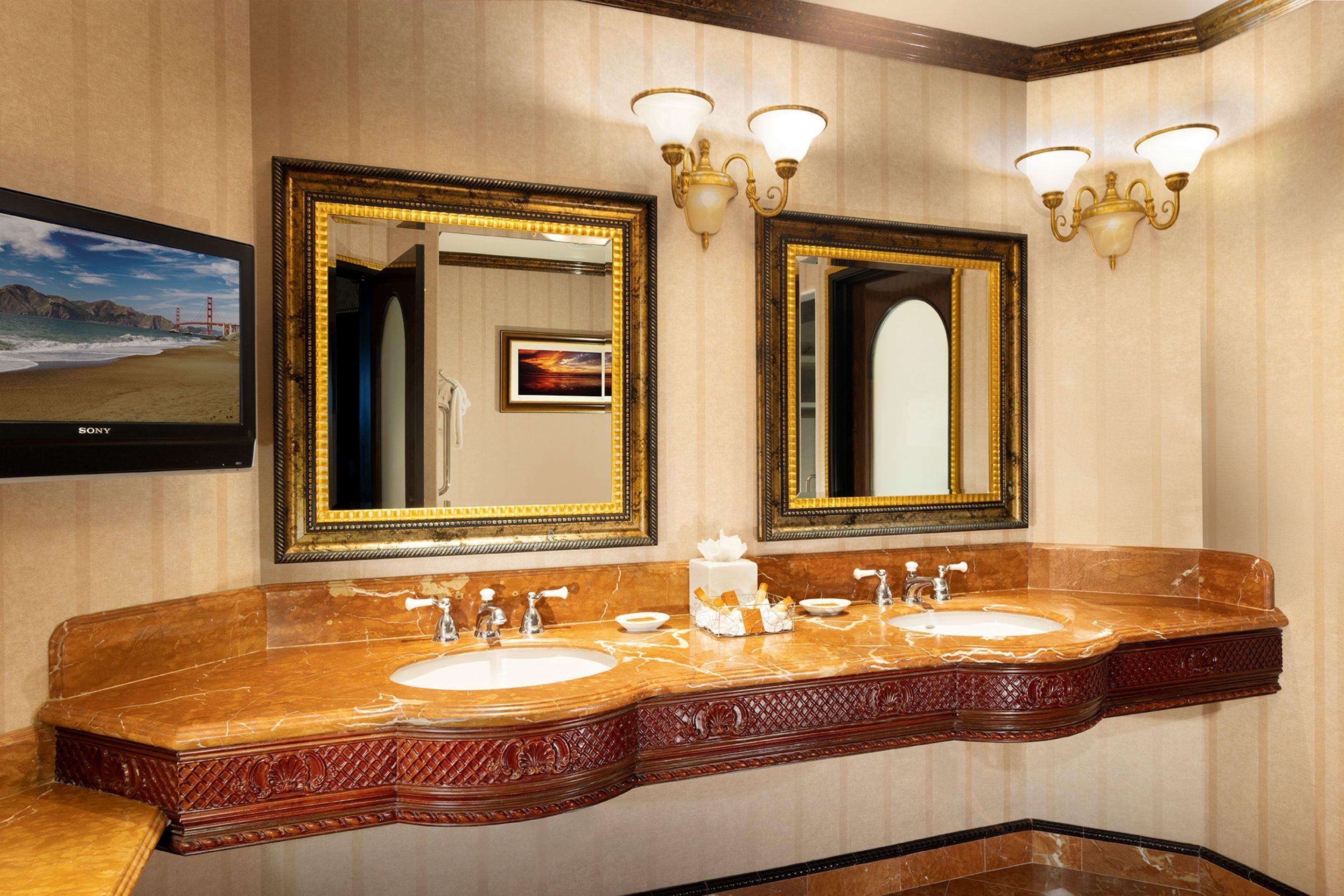 Un bagno con due lavandini, uno specchio grande, applique e un quadro incorniciato.