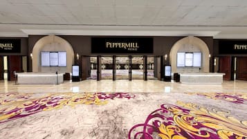 A hotel lobby with a check-in desk, a reception area, and a decorative floor pattern.