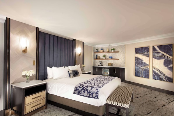 A modern hotel room with a large bed, bedside tables, a bench, a small kitchenette, and artwork on the walls. - Peppermill Resort Spa Casino, WorldHotels Elite (Reno)