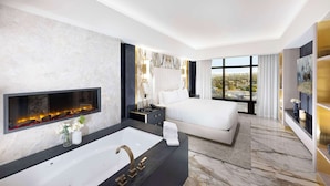 Une chambre d’hôtel moderne dotée d’un grand lit, d’une cheminée intégrée, d’une grande fenêtre offrant une vue sur la ville et d’un sol en marbre.