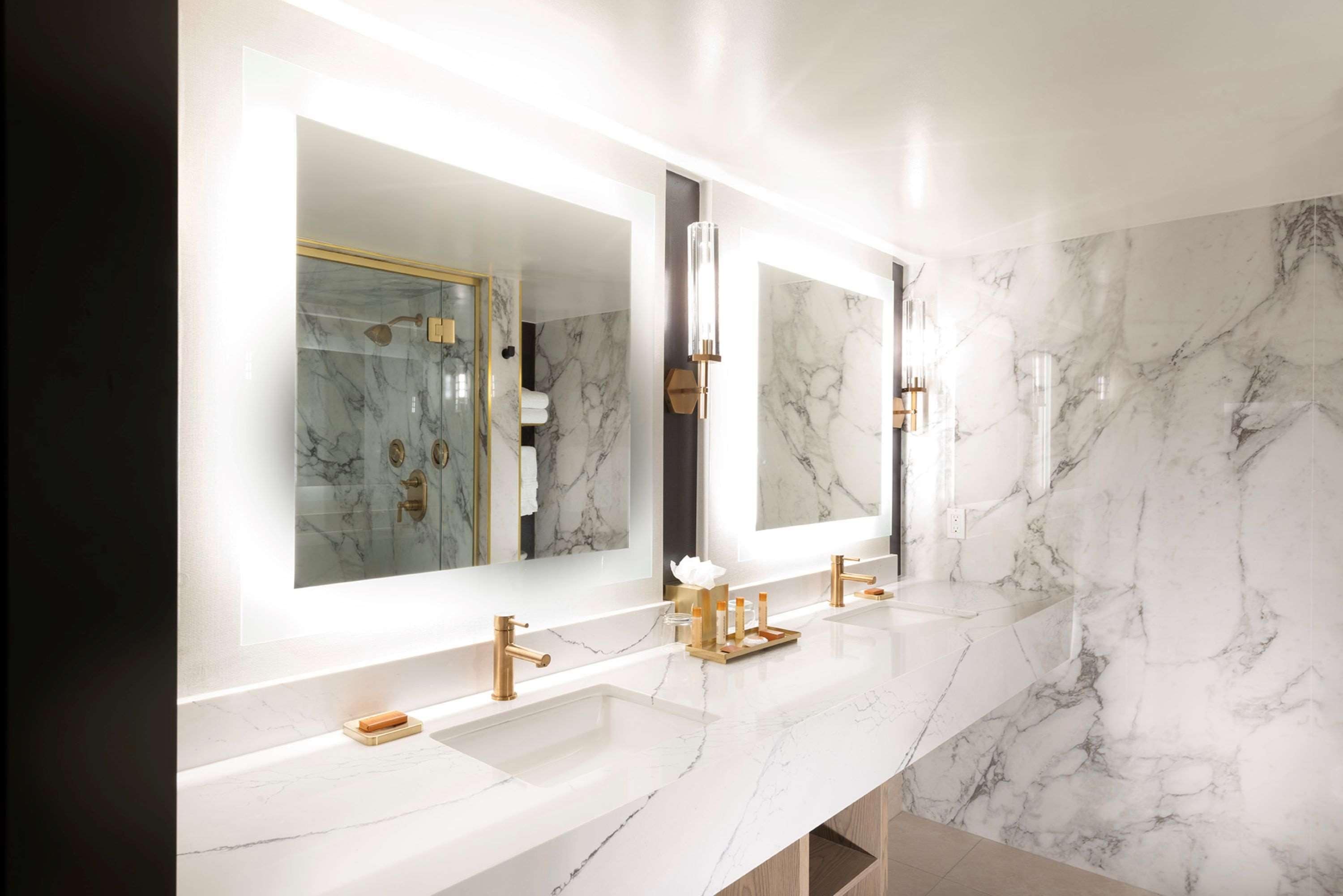 Un baño moderno con paredes de mármol y dos lavamanos.