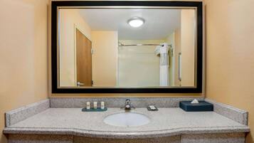 A bathroom with a granite sink, a mirror, and a towel rack.