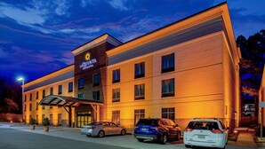 Un hotel con un letrero llamativo, varios espacios de estacionamiento y una entrada techada.