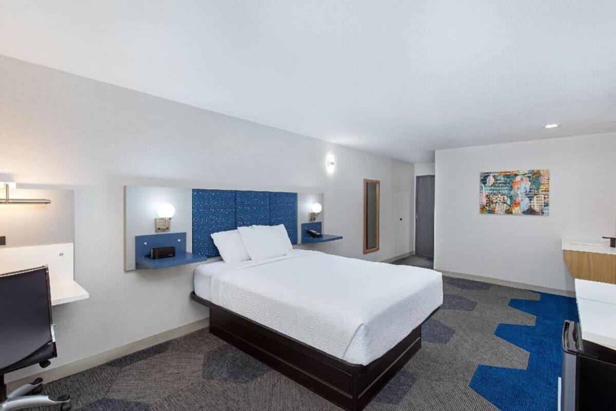A hotel room with a bed, bedside tables, a desk, and a chair.