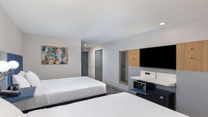 A hotel room with a large bed, a desk with a computer, a flat-screen TV mounted on a wooden cabinet, and a small kitchenette. - Microtel Inn & Suites by Wyndham Manchester (Manchester)