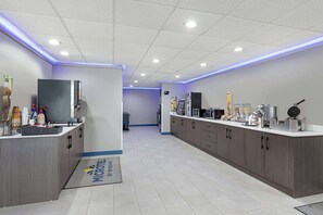 A modern hotel lobby with a reception desk, a microwave, a coffee machine, and a waffle maker. - Microtel Inn & Suites by Wyndham Manchester (Manchester)