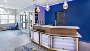 A reception desk with a 'WELCOME' sign, a blue wall, and pendant lights. - Microtel Inn & Suites by Wyndham Manchester (Manchester)