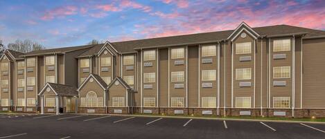 A multi-story hotel with a parking lot in front.