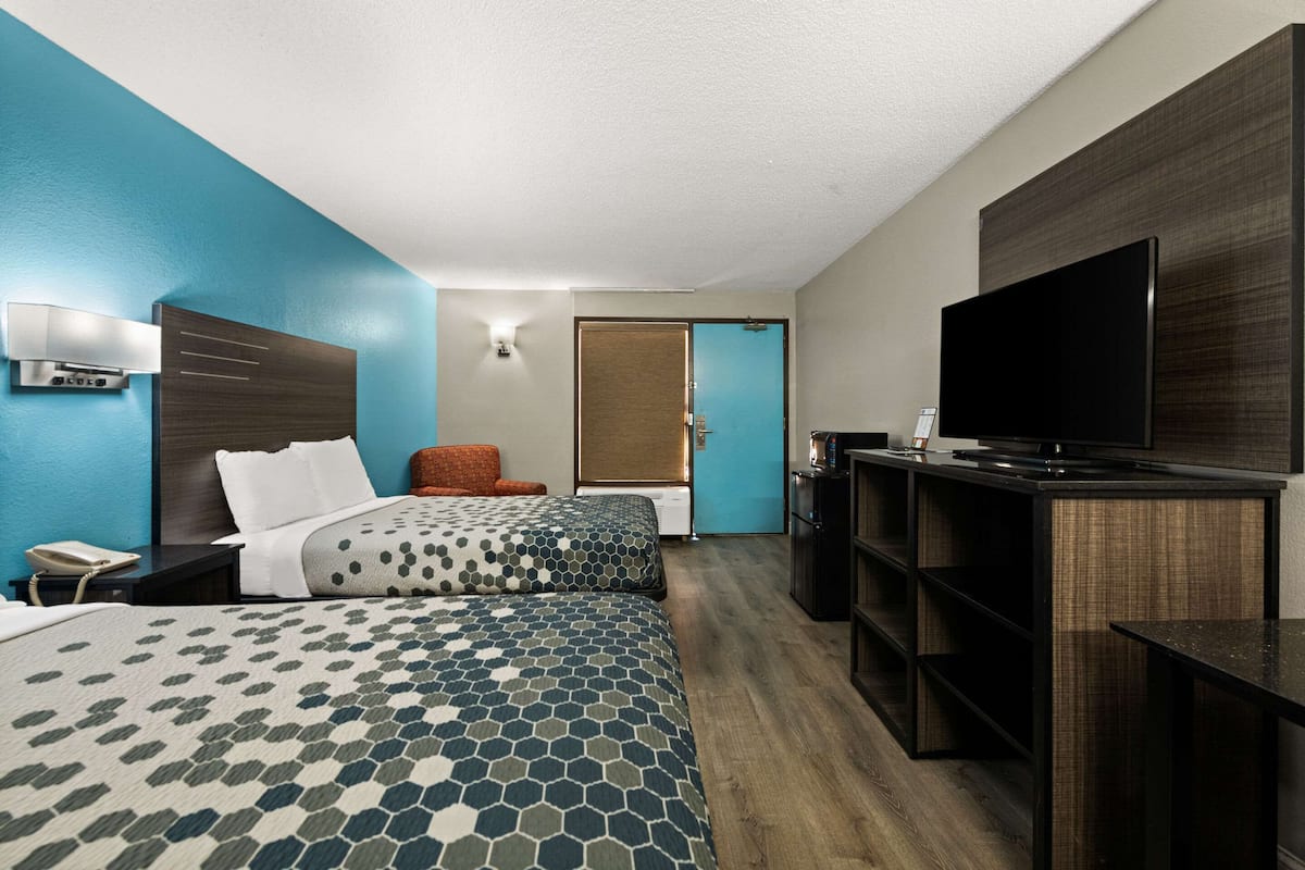 A hotel room with two beds, a TV, a desk, and a chair.