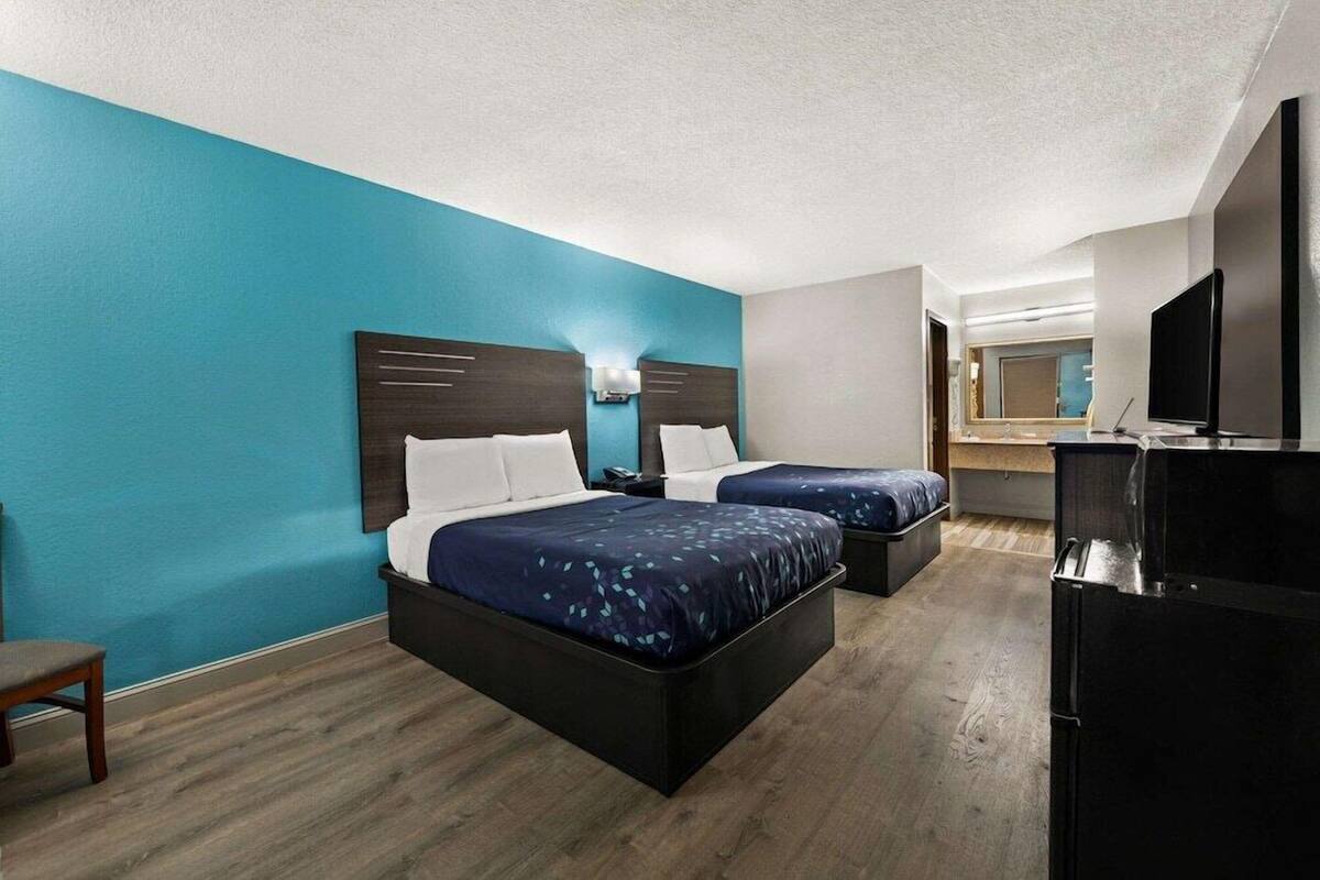 A hotel room with two beds, a TV, and a refrigerator.