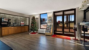 Hall moderna di un hotel con una reception in legno, un albero di Natale e un'ampia finestra con vista sull'esterno.